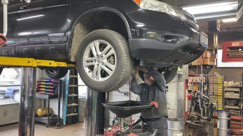 A technician inspecting the underside of a lifted vehicle