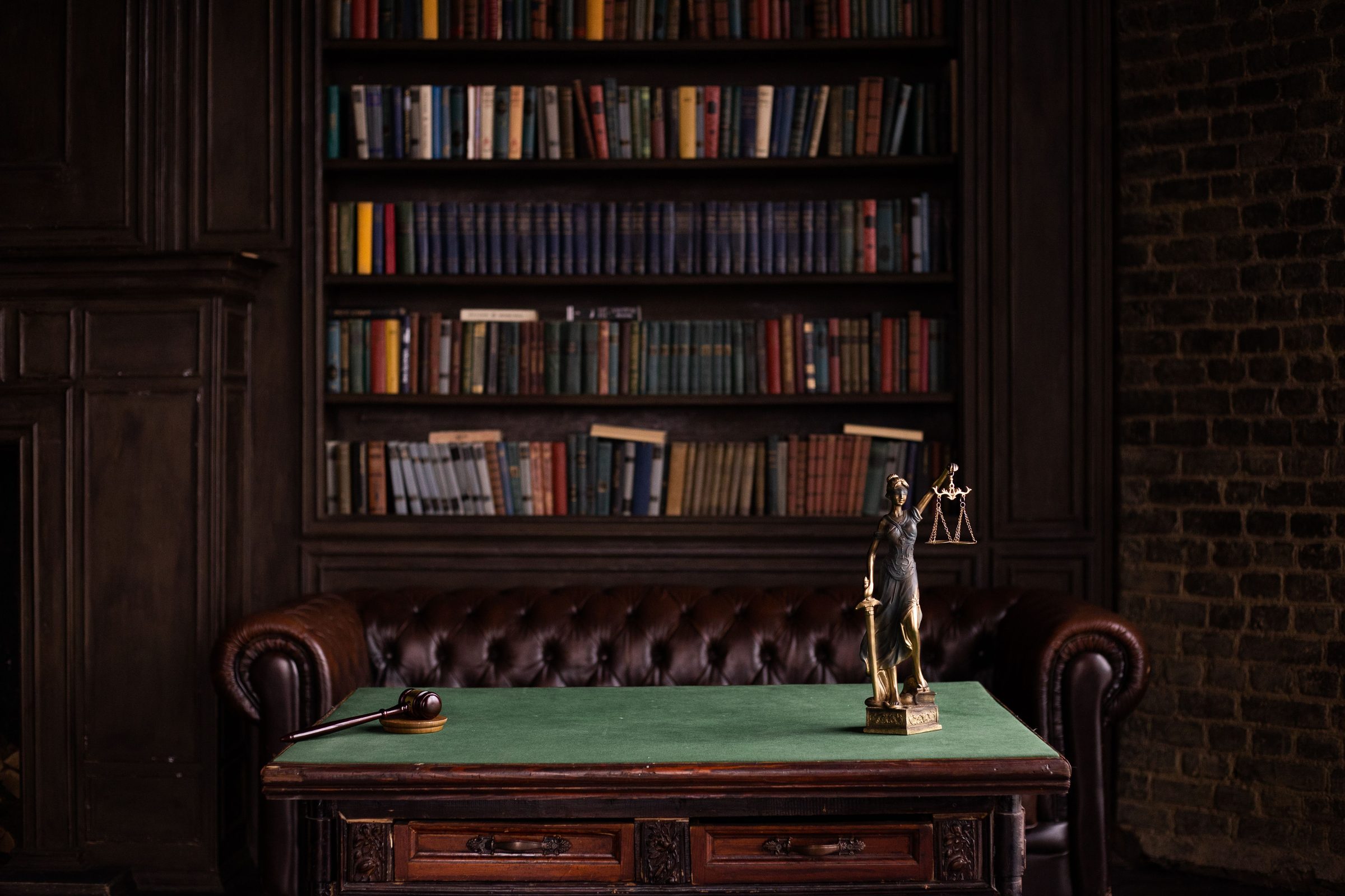 Law office library with leather chesterfield, antique desk, gavel and scales of justice